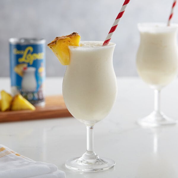 A glass of white liquid with a straw and pineapple slice.