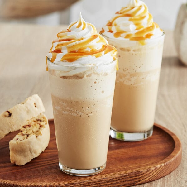 Two glasses of Frozen Bean Caramel Macchiato with whipped cream and caramel sauce.