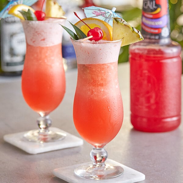 Two glasses of Finest Call Hurricane drinks with fruit on top.