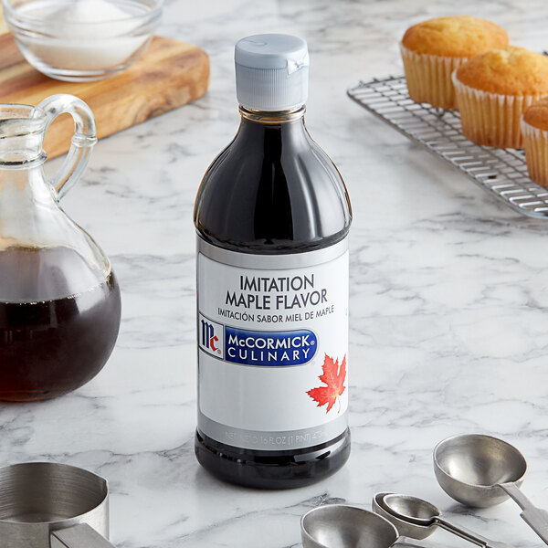 A McCormick Culinary Imitation Maple Extract bottle next to muffins on a counter.