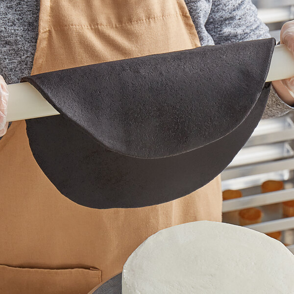 A person holding a black box of Satin Ice Dream Onyx Black Chocolate-flavored Rolled Fondant.