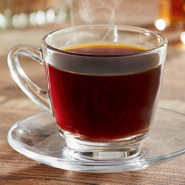 A glass of Ellis William Penn coffee on a saucer with a spoon.