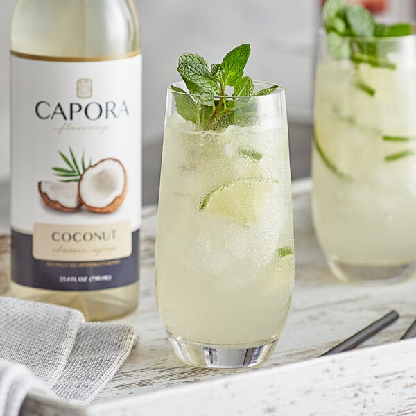 A glass of coconut and lime drink made with Capora Coconut Flavoring Syrup on a white background.