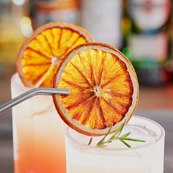 Blue Henry dried blood orange slices in two glasses of orange juice with orange slices on the rim.