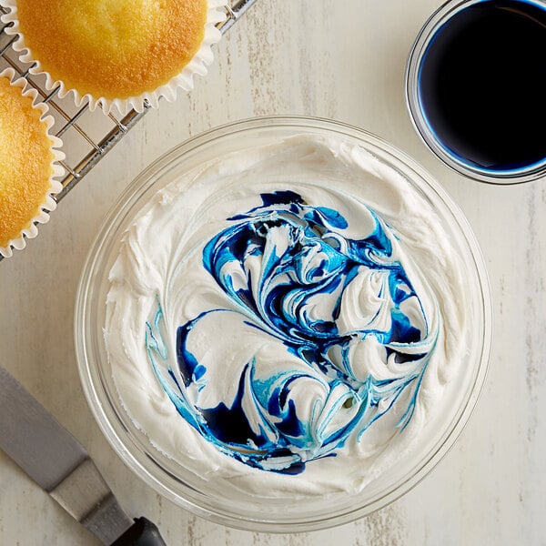 A bowl of frosting with blue and white swirls on a cupcake.