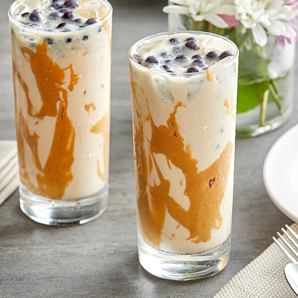 Two glasses of milkshakes made with Fanale peanut butter powder, topped with caramel sauce and blueberries.