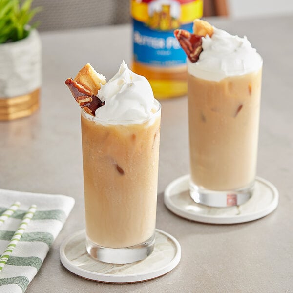 Two glasses of iced coffee with whipped cream and Torani Butter Pecan flavoring syrup.