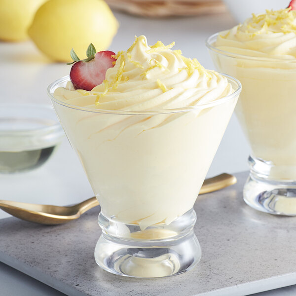 Two glasses of lemon curd with strawberries and whipped cream.