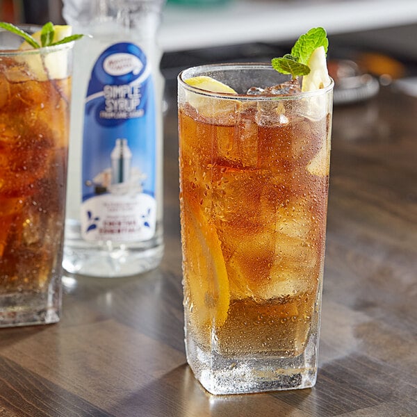 A glass of iced tea with lemon slices and mint next to a bottle of Master of Mixes Simple Syrup.