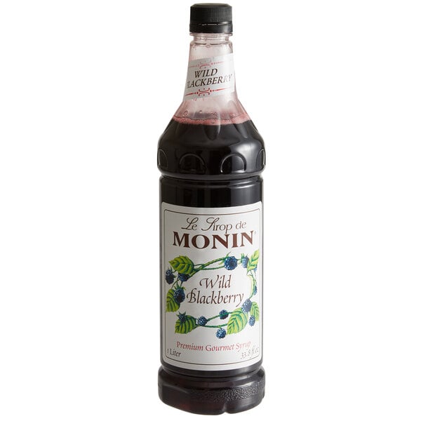 A close up of a Monin Wild Blackberry Syrup bottle filled with black liquid.