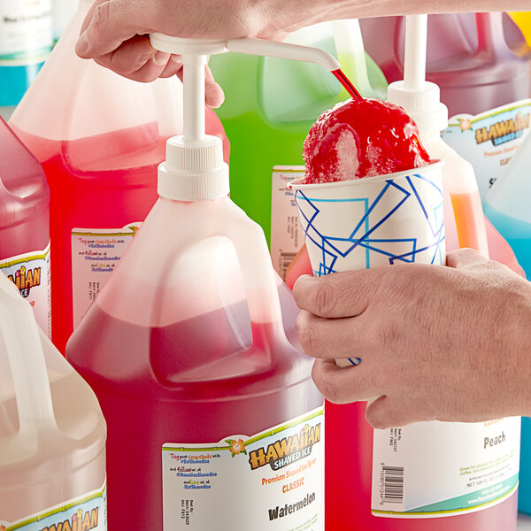 A person pouring Hawaiian Shaved Ice Watermelon Snow Cone Syrup from a plastic jug with a white cap into a cup.