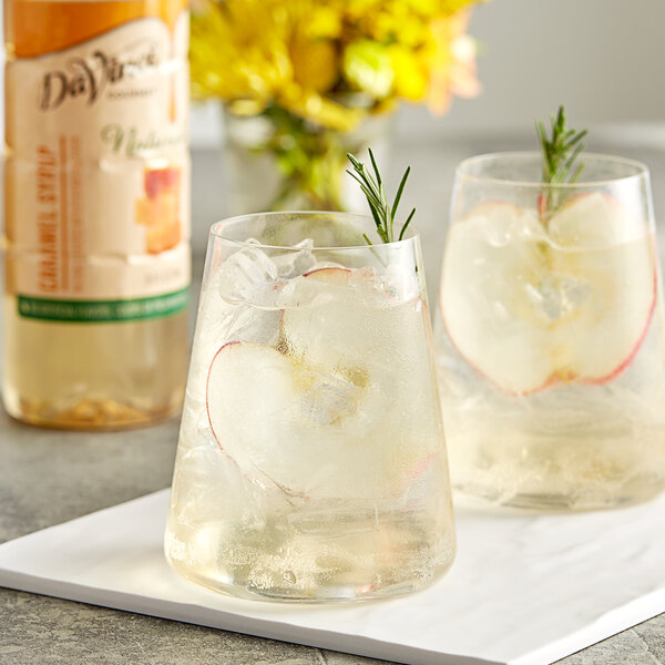 Two glasses of caramel apple drinks with ice and rosemary sprigs using DaVinci Gourmet Caramel Flavoring Syrup.