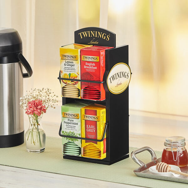 A Twinings double-sided spinning tea rack on a table with tea bags in it.