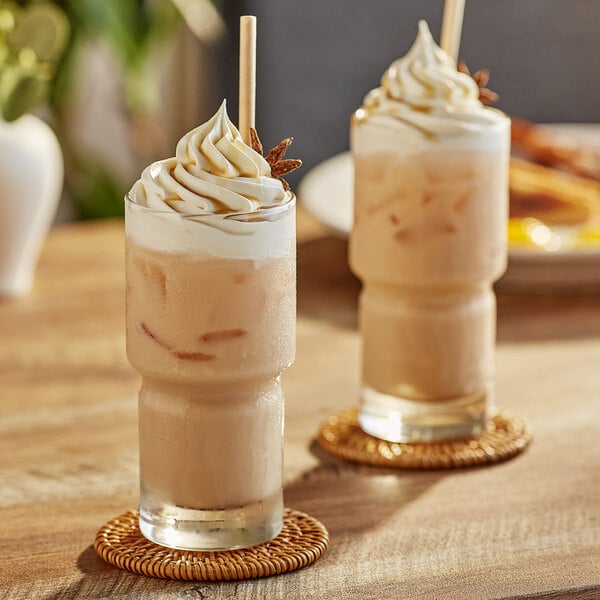 A table with two glasses of Capora Chai Tea Lattes with cinnamon on top.