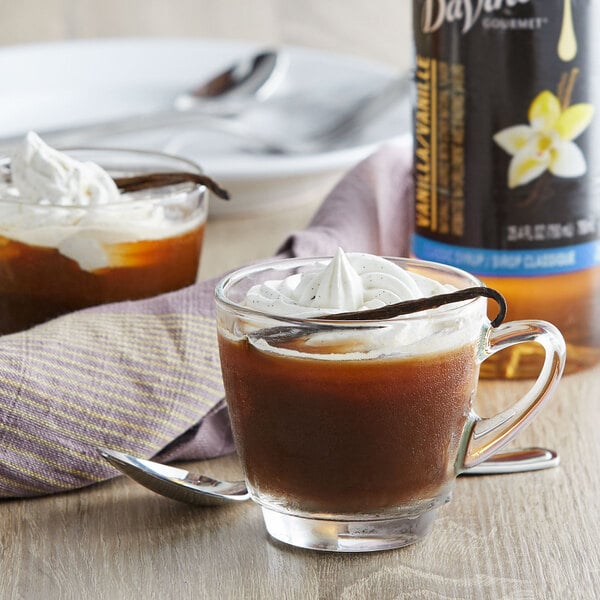 a glass mug with brown liquid and whipped cream