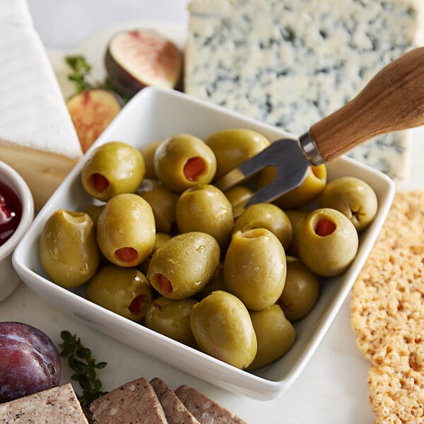 A bowl of green olives with a fork.