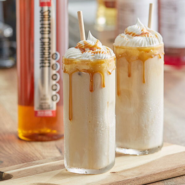 A glass of liquid with whipped cream and caramel sauce on a table.
