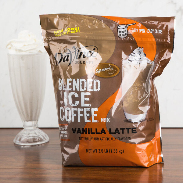 A plastic bag of DaVinci Gourmet Vanilla Latte Mix next to a glass of milk.