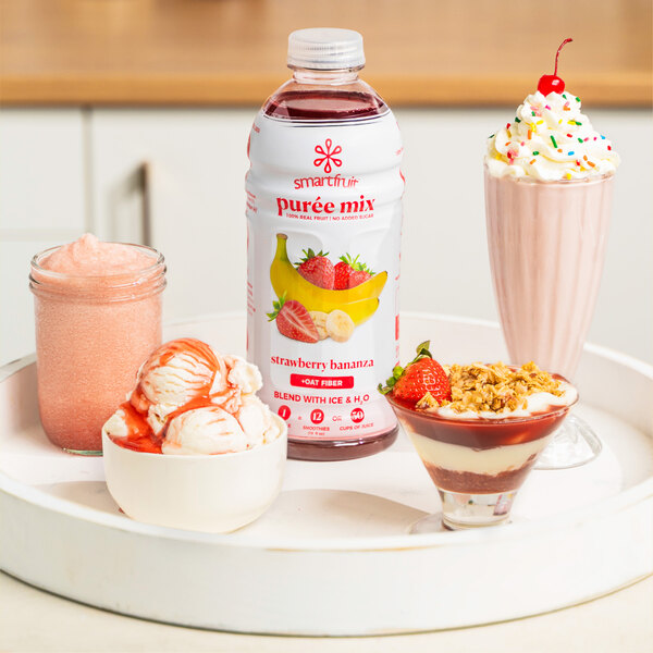 A white tray of desserts with a pink glass of Smartfruit Strawberry Bananza puree on the side.