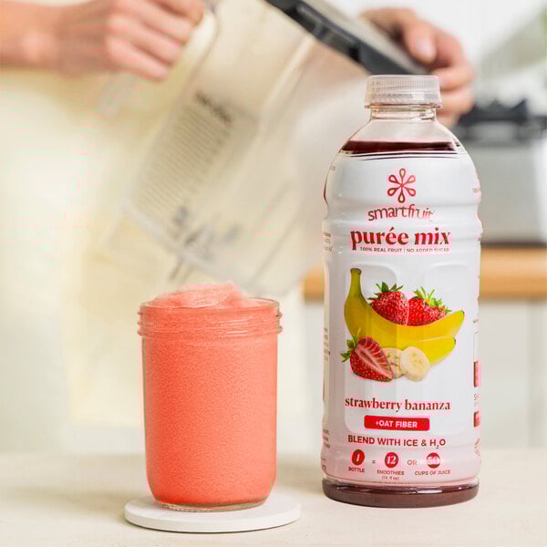 A woman uses a blender to mix Smartfruit Strawberry Bananza smoothie.