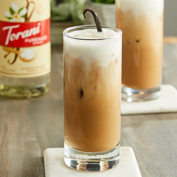 A glass of iced coffee with Torani vanilla syrup on a white background.