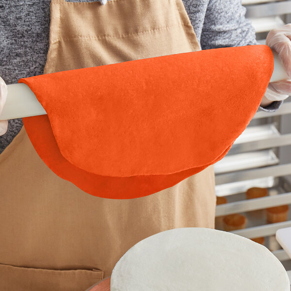 A person rolling out Satin Ice Orange Rush rolled fondant with a rolling pin.