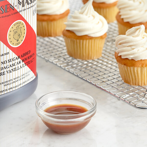 A close-up of a cupcake with white frosting and a bottle of brown liquid.