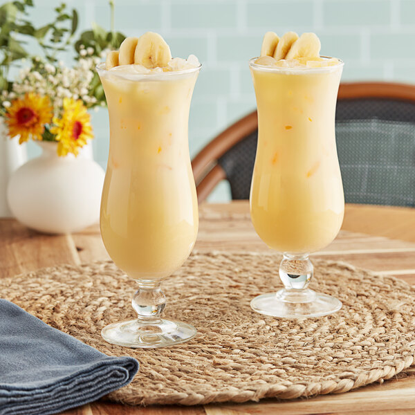 Two glasses of yellow Fanale Banana smoothie on a table.