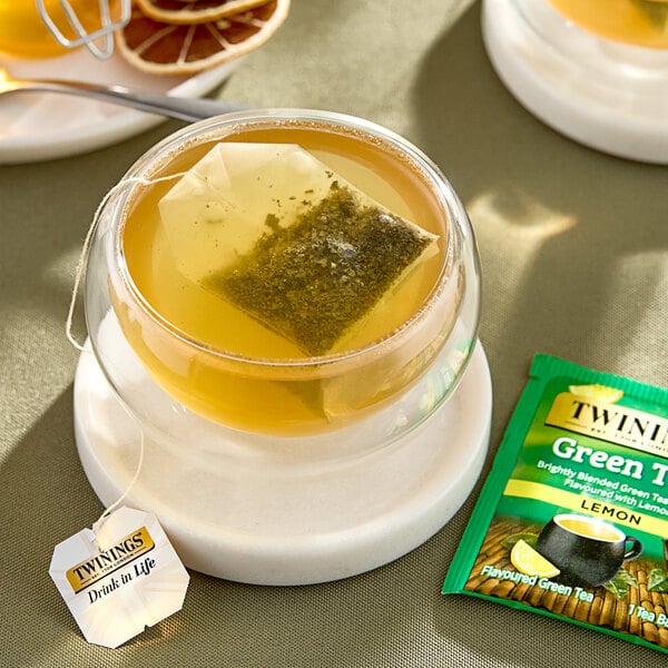 A glass cup of Twinings Green Tea with Lemon with a bag in it.