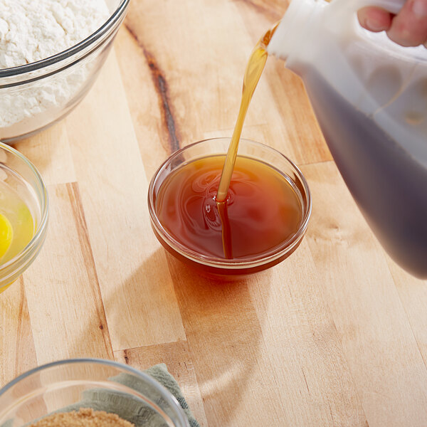 A person pouring brown liquid from a pitcher into a bowl of brown liquid.