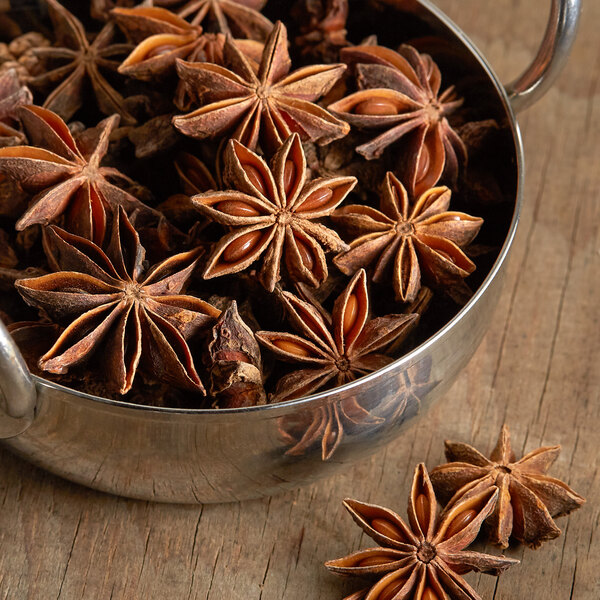 A metal bowl of Regal Whole Star Anise on a table.