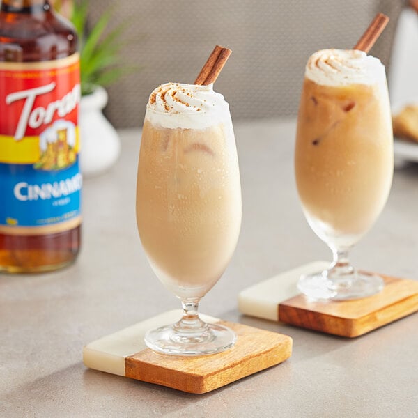 Two glasses of iced coffee with Torani Cinnamon Flavoring Syrup and straws on a white background.