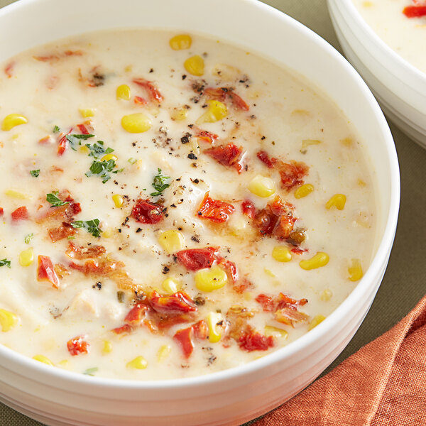 A bowl of soup with diced red bell pepper and other vegetables.