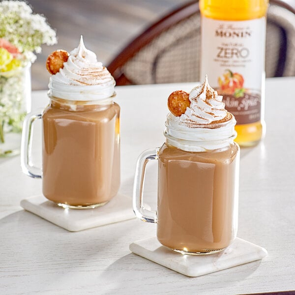 A glass mug of coffee with Monin Pumpkin Spice syrup and whipped cream on top.