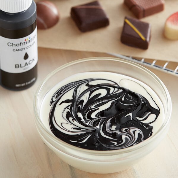 A bowl of white liquid with black swirls using Chefmaster Black Oil-Based Candy Color.
