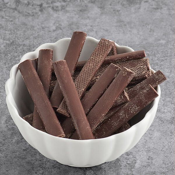 A bowl of Cacao Barry chocolate batons on a gray surface.