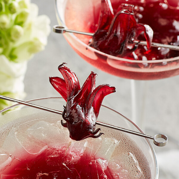 A close-up of a glass of red liquid with a Wild Hibiscus flower inside.