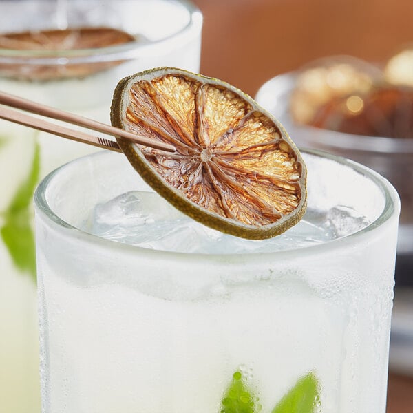 A close-up of a dried lime slice in a glass of ice.