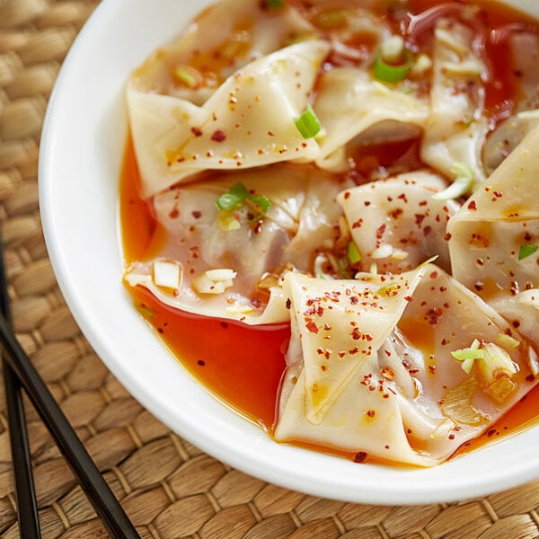 A bowl of soup with dumplings and Lee Kum Kee Chili Oil with chopsticks.