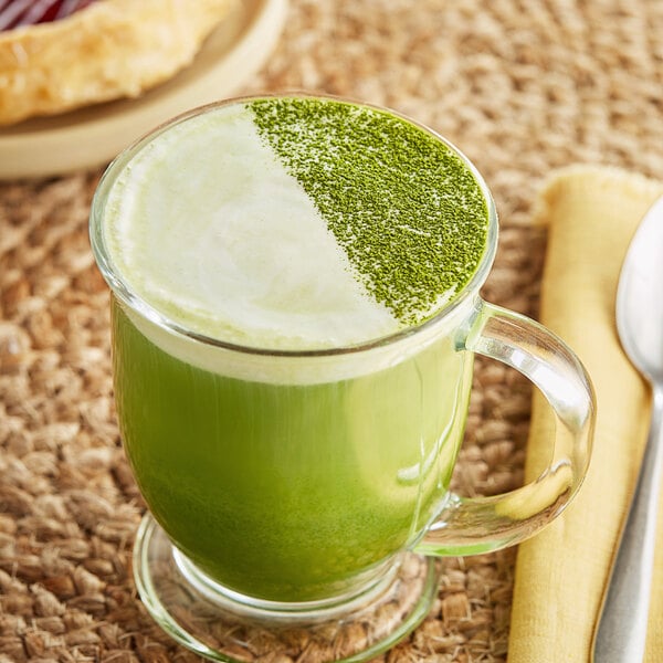 A glass mug of green Tenzo matcha tea with green sprinkles on top.
