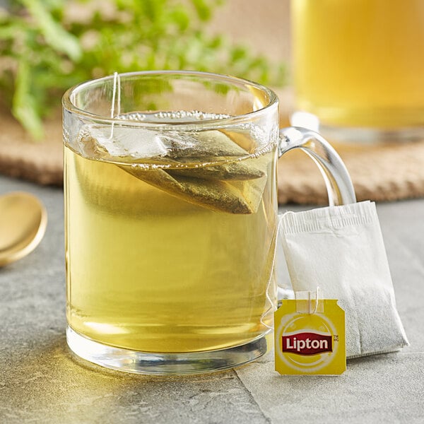 A glass mug of Lipton Classic Green Tea with a tea bag in it.