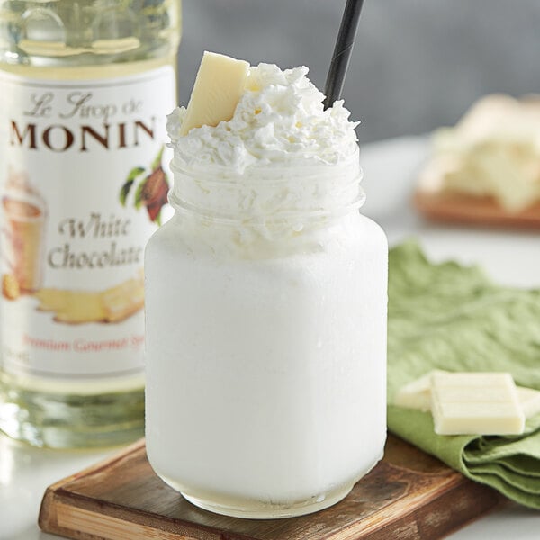 A glass jar with a straw and white liquid with a white label.