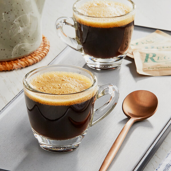 Two cups of Lavazza Espresso Maestro Dek coffee on a tray with a spoon.