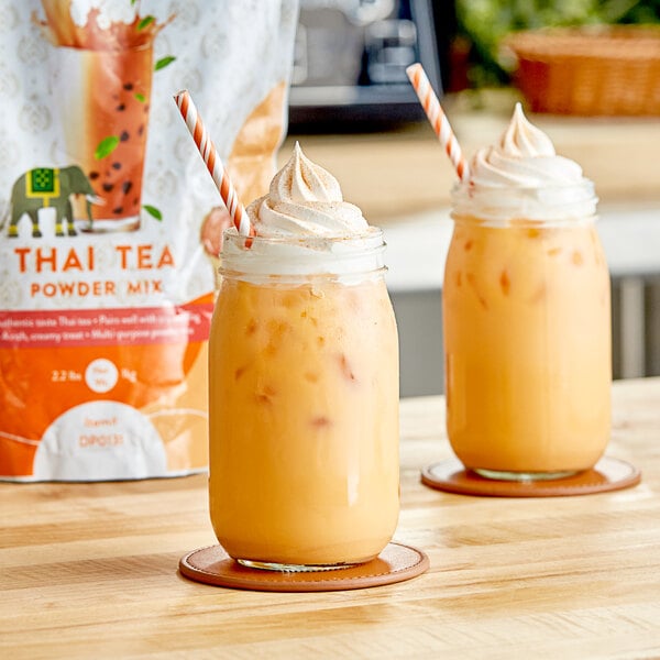 Two mugs of Thai tea with orange liquid and straws.