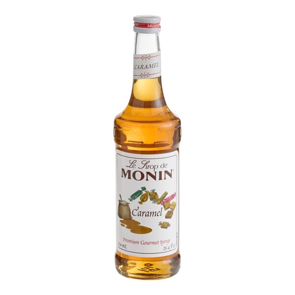 A clear glass bottle filled with amber-colored liquid and labeled as Monin caramel syrup.