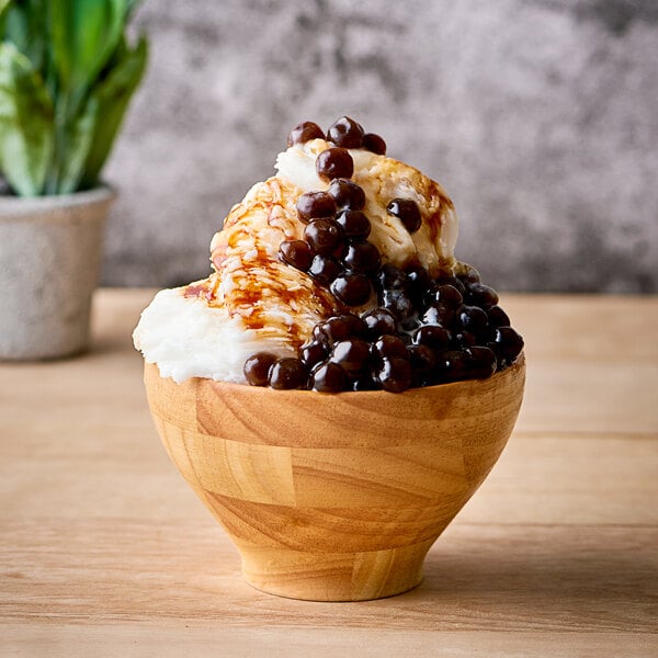 A bowl of milk snow ice with black balls and syrup.