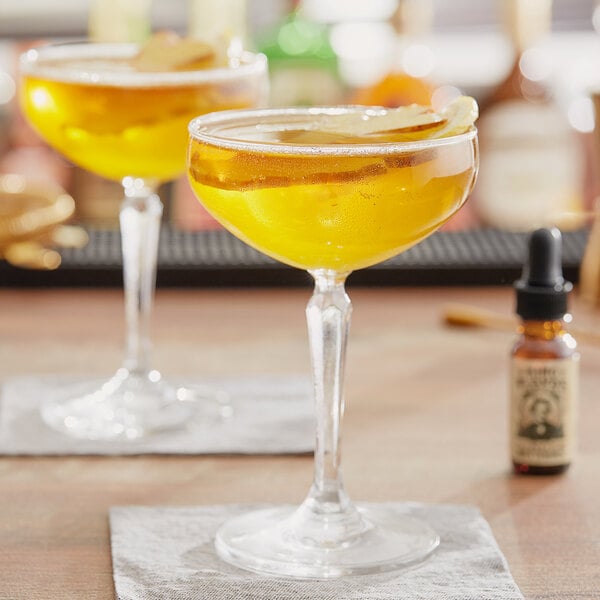 A table in a cocktail bar with a glass of yellow liquid and a bottle of King Floyd's Ginger Bitters.