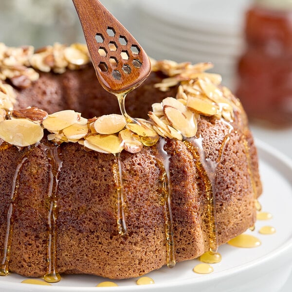 A bundt cake with almonds and honey drizzled on top.