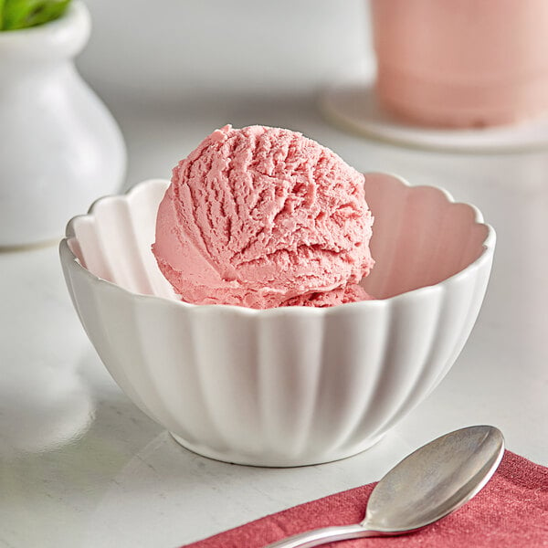 A bowl of pink ice cream with a spoon on a red napkin.