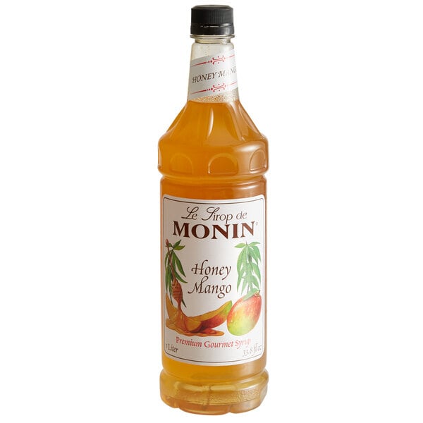 A bottle of Monin Premium Honey Mango syrup with orange liquid and a white label.